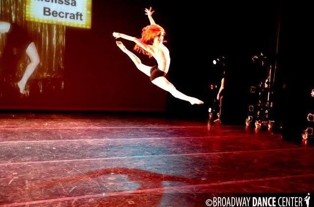 Mid-air split leap on a dark stage, Broadway Dance Center watermark