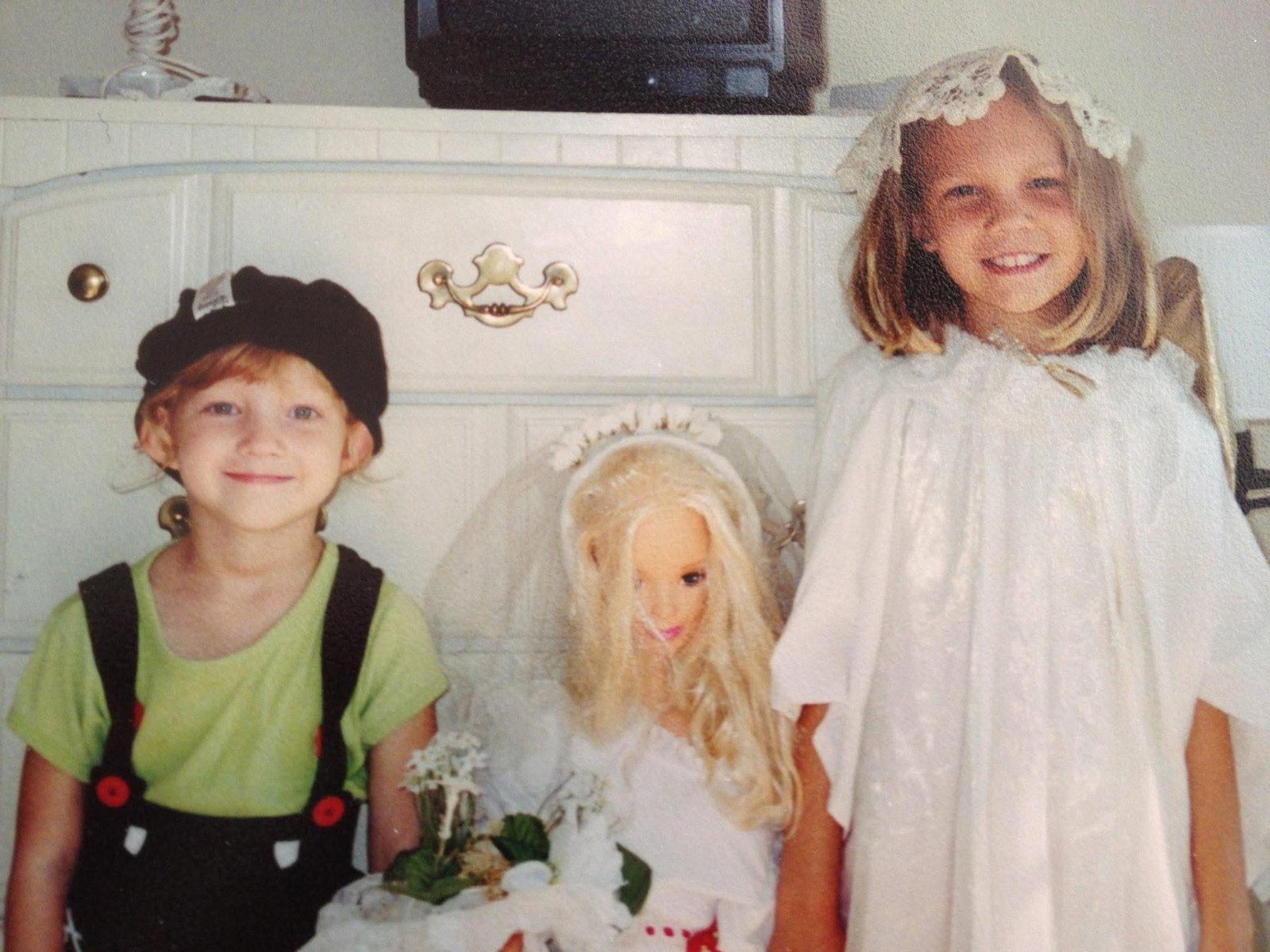 Two kids holding a Barbie bride doll between them, film snapshot