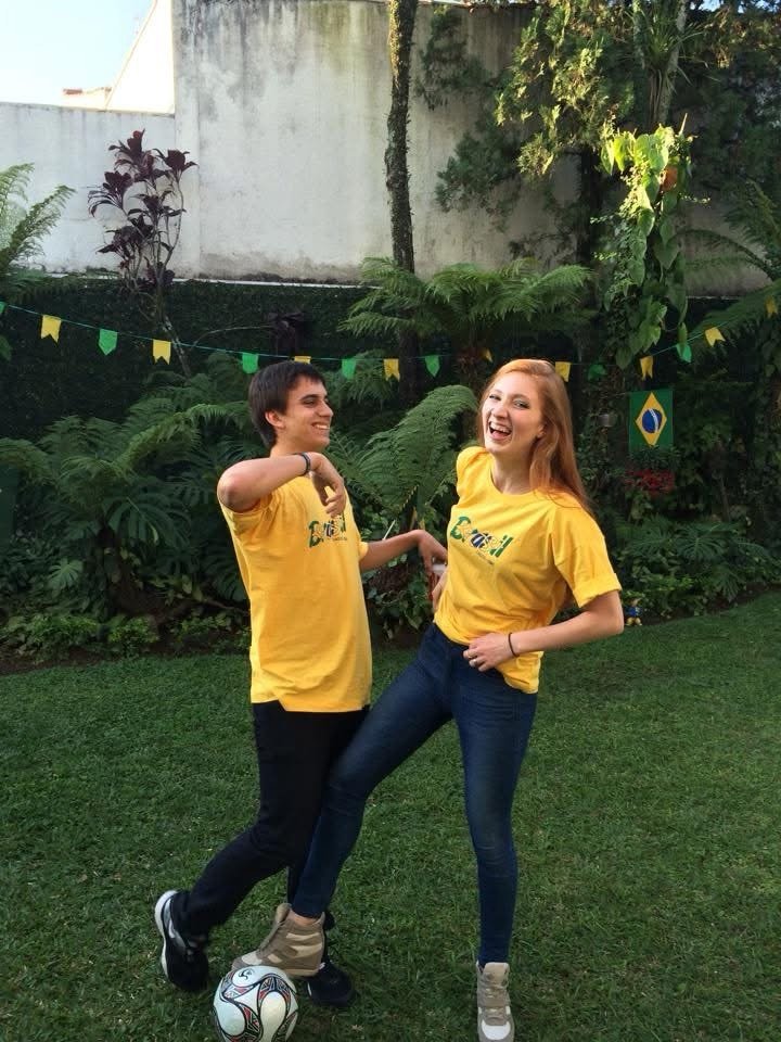 Couple in matching yellow Brasil tees in a tropical backyard