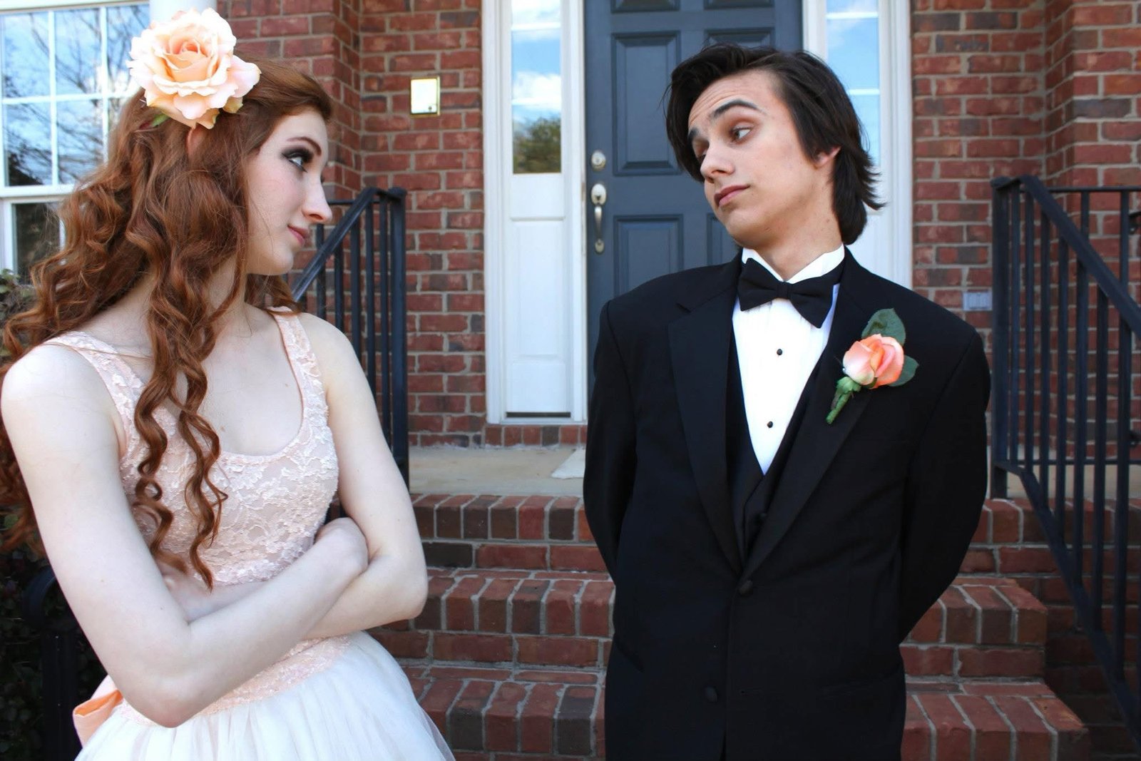 Melissa in a blush prom dress and her boyfriend in a tux on the front steps
