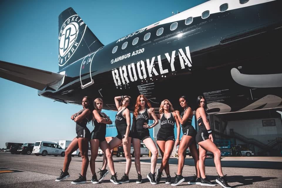 Brooklynettes squad posed in front of the Nets-livery JetBlue A320
