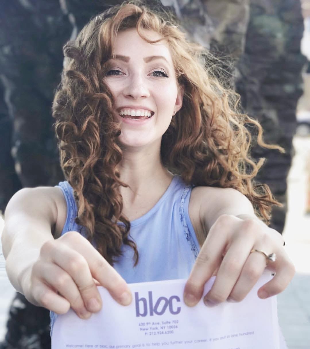 Melissa holding out the bloc agency welcome packet, big smile