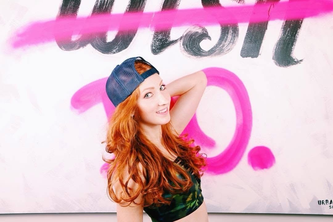 Posed against a pink-and-black WISH graffiti mural, backwards snapback