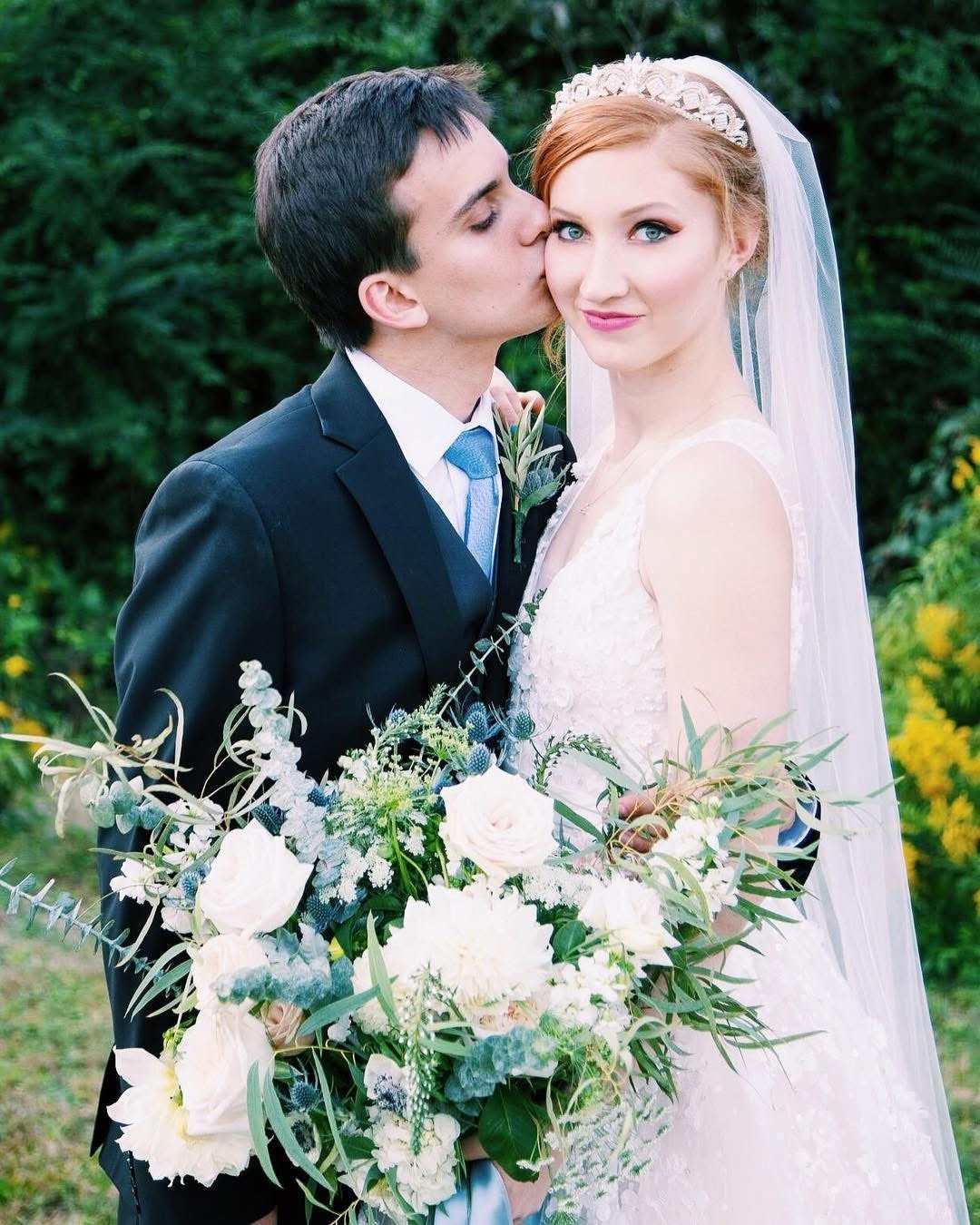 Newlyweds outdoors, Luis kissing Melissa's cheek